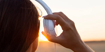 Back view of woman admiring sunset with headphones on