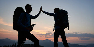 Couple hikers giving high five during sunset in mountains
