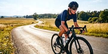 Cyclist riding in direct afternoon sunlight on an open road.