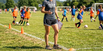 Youth sports coach standing on a sunny sideline during summer practice.